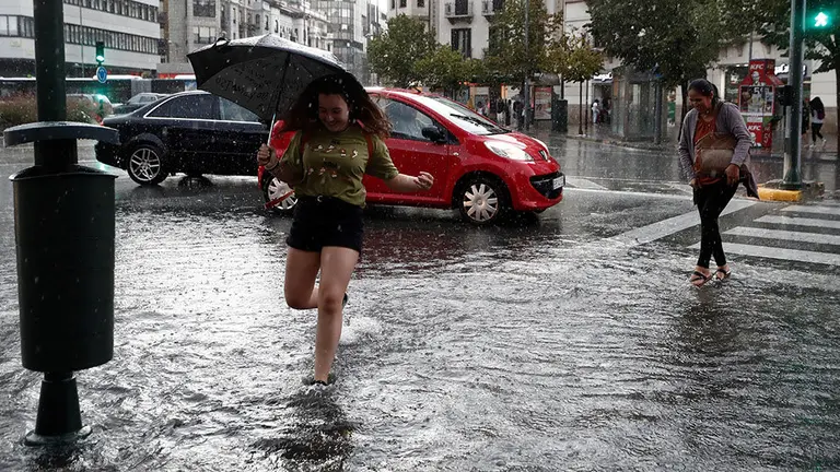 GRAFCAV8055. PAMPLONA (NAVARRA), 18/09/2019.- Varias personas cruzan la Avenida Baja Navarra que se encuentra inundada de agua tras la fuerte tormenta de esta tarde que ha ocasionado numerosas balsas en las carreteras y donde los bomberos han realizado numerosas salidas para achicar agua en Pamplona. EFE/ Jesús Diges