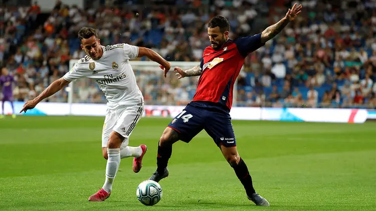 El delantero español del Real Madrid Lucas Vázquez (i) disputa un balón con Rubén García, centrocampista español del Osasuna, durante el partido entre ambos equipos correspondiente a la sexta jornada de LaLiga Santander que se disputa este miércoles en el estadio Santiago Bernabéu de Madrid. EFE/ Juanjo Martín
