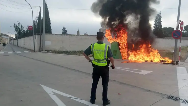 Un agente de la Guardia Civil, junto a uno de los contenedores quemados. GUARDIA CIVIL