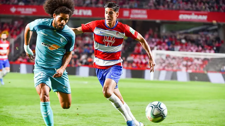 El defensa de Osasuna, Aridane Hernández (i), persigue el balón ante el delantero del Granada, Carlos Fernández, durante el encuentro correspondiente a la jornada novena de primera división que disputan esta noche en el Nuevo Estadio Los Cármenes, en Granada. EFE / Miguel Angel Molina.