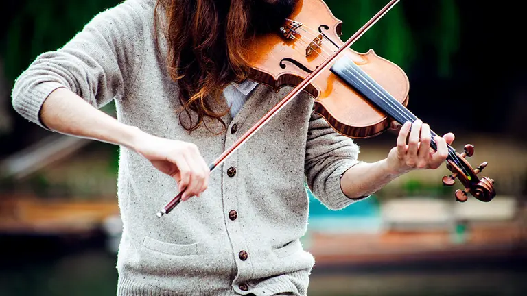 Un mujer interpreta una pieza con un viol&iacute;n en la calle.
