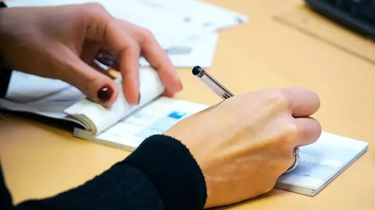 Una mujer firma un cheque en un banco ARCHIVO