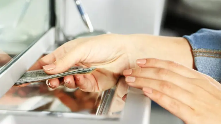 Una mujer retira dinero en la ventanilla de un banco ARCHIVO
