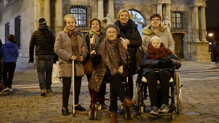 El alcalde, Enrique Maya, recibe a personas de residencias de la tercera edad que recorren en taxi la ciudad para ver las luces y el ambiente navideño de Pamplona. IÑIGO ALZUGARAY