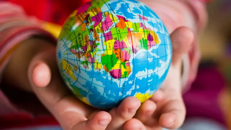 Un niño sostiene una bola del mundo en sus manos. ARCHIVO