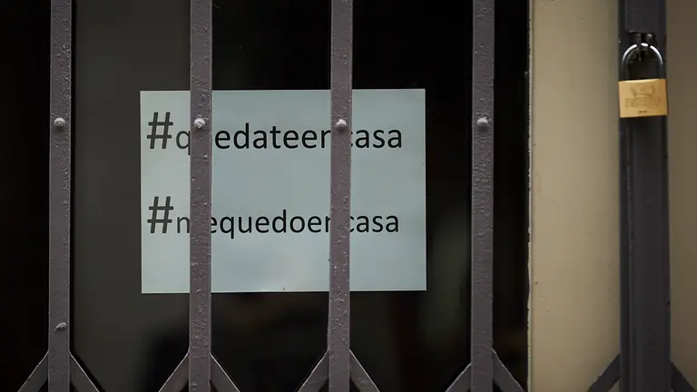 Un cartel con el lema “quédate en casa” y “me quedo en casa” en una tienda cerrada curante el Estado de alerta por el coronavirus. PABLO LASAOSA