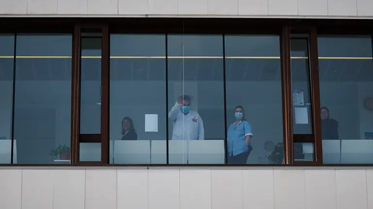 Un médico saluda por un ventanal del centro de salud de Buztintxuri durante la crisis del coronavirus. PABLO LASAOSA