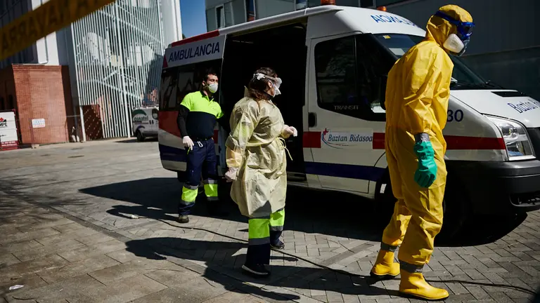 Un mimbro de la DYA lleva a una sanitaria al túnel de desinfección para quitar los EPIs durante la crisis del coronavirus. PABLO LASAOSA 