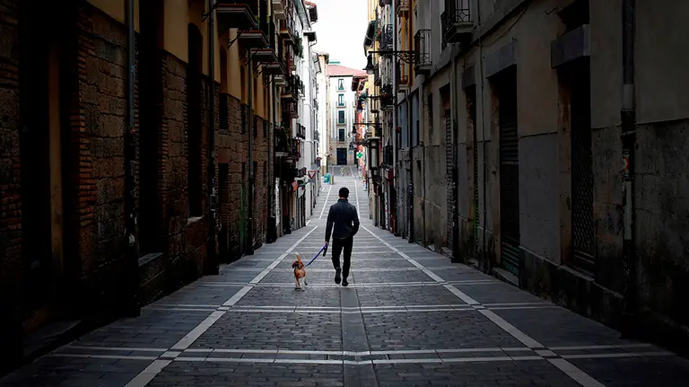 -FOTODELDIA- GRAF2585. PAMPLONA, 28/03/2020.- Una persona pasea a su perro por una calle desierta del casco histórico de Pamplona este sábado durante la segunda semana de confinamiento con el objetivo de prevenir la propagación del coronavirus. EFE/Villar López
