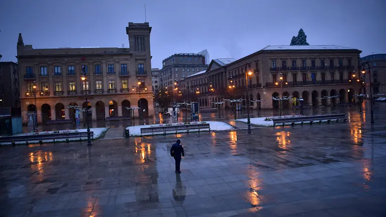 Una persona camina por la Plaza del Castillo durante la nevada mañana del decimoséptimo día de confinamiento por el coronavirus. PABLO LASAOSA