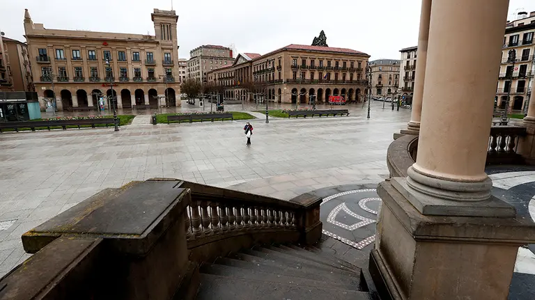 GRAFCAV4104. PAMPLONA, 01/04/2020.- Una persona atraviesa una solitaria Plaza del Castillo de Pamplona después de que el pasado lunes el gobierno anunciara la ampliación del confinamiento tras la declaración del estado de alarma en el que el sector de la construcción ha sido uno de los mas afectados.  EFE/Jesús Diges
