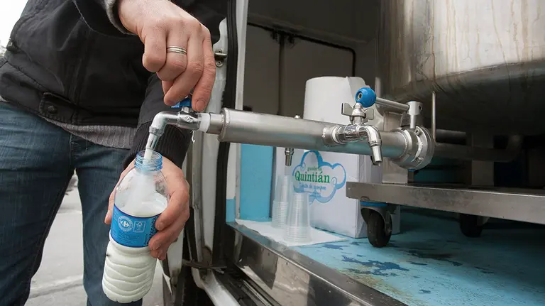 Un ganadero llena una botella con leche durante el reparto de leche gratuito. EFE/Eliseo Trigo/Archivo
