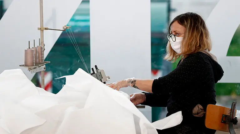 GRAFCAV4321. PAMPLONA, 07/04/2020.- Unas 20 personas en turnos de mañana y tarde están cosiendo batas de gran valor en el sector sociosanitario para proteger al personal que se enfrenta a la pandemia de coronavirus. Se trata de hombres y mujeres que saben coser con máquinas industriales y que en este momento están en paro, en situación de ERTE o bien en activo en los trabajos esenciales que todavía se prestan, así el departamento de Salud recibirá diariamente 600 batas de protección de esta solidaria y voluntaria factoria ubicada en REFENA.  EFE/ Jesús Diges
