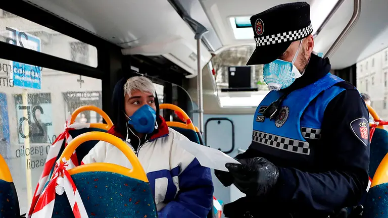 Un policía municipal de Pamplona solicita el justificante de desplazamiento al pasajero de una villavesa durante la crisis por el coronavirus. EFE/ Jesús Diges