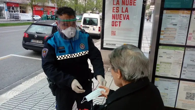 Un agente entrega una mascarilla en una parada de la villavesa en este martes marcado por el regreso a la actividad laboral. POLICÍA MUNICIPAL DE PAMPLONA