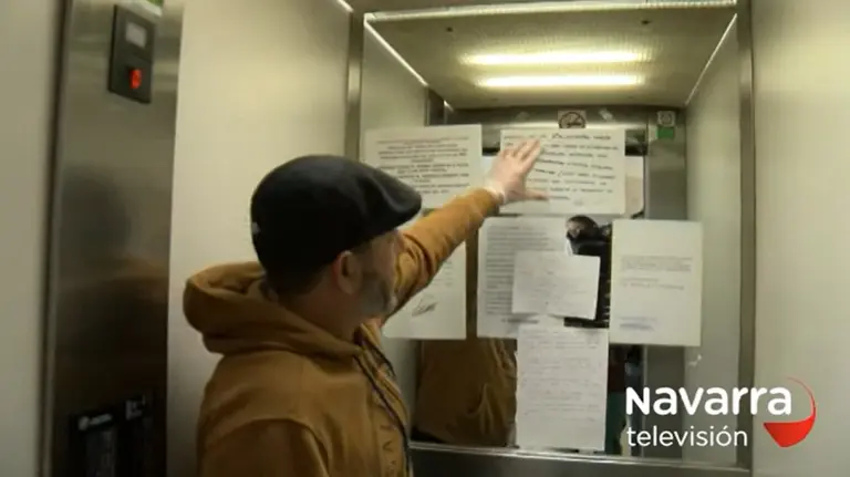 Un vecino muestra la respuesta a la nota que reclamaba en un portal de la Rochapea que los trabajadores de supermercados se mudasen. NAVARRA TELEVISIÓN