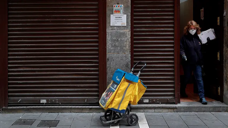 GRAFCAV4748. PAMPLONA, 20/04/2020.- Una trabajadora de Correos en Pamplona sale de un domicilio durante el reparto de la correspondencia este lunes en el casco histórico de Pamplona en una jornada en la que los sindicatos UGT y CCOO han lamentado las "elevadas cifras" de la incidencia del coronavirus entre los empleados de Correos, con un total de 82 casos en Navarra según los últimos datos facilitados por Correos el 13 de abril. EFE/Villar López

