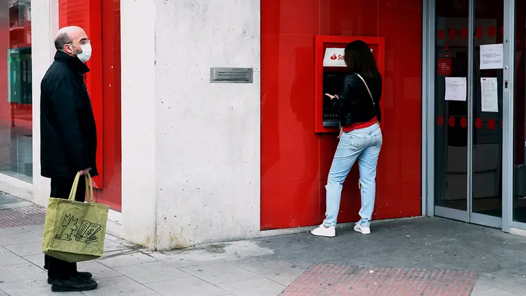 Un hombre con mascarilla espera su turno mientras una mujer saca dinero de un cajero de ING un día después de que Banco Central Europeo (BCE) haya especificado que decidirá "banco a banco" la hoja de ruta para recuperar los niveles de capital y liquidez previos a la crisis generada por la pandemia del coronavirus Covid-19, debido a que todavía existe incertidumbre sobre la extensión del impacto económico, en Madrid (España), a 21 de abril de 2020.

BANCO CENTRAL EUROPEO;BANCA;CORONAVIRUS;

21/4/2020