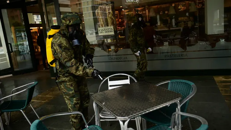 Un militar el Regimiento América 66 de Pamplona desinfecta los alrededores de un establecimiento de alimentación. PABLO LASAOSA
