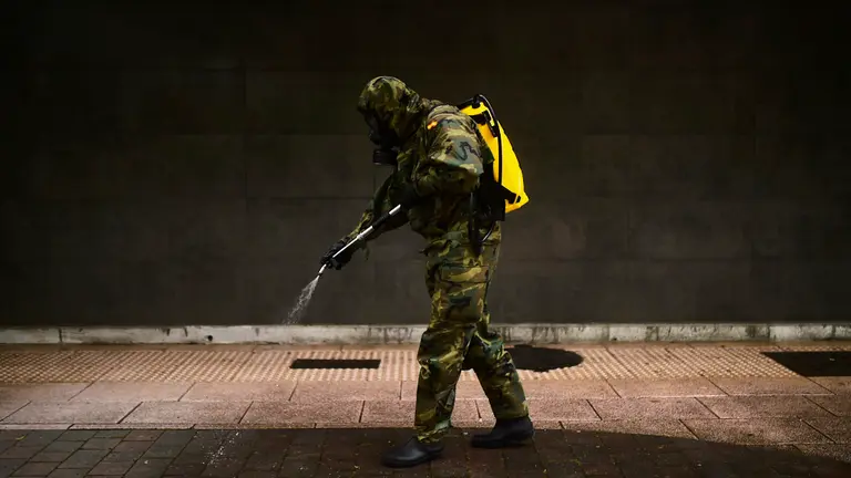 Un militar del Regimiento América 66 desinfecta las inmediaciones de de una farmacia este miércoles por la mañana. PABLO LASAOSA
