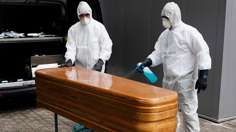GRAFCAV4782. PAMPLONA, 22/04/2020.-  Trabajadores de un tanatorio de Pamplona sacan del Hospital de Navarra un ataúd para proceder a su desinfección antes de trasladarlo al cementerio. La Asociación Nacional de Servicios Funerarios (PANASEF) ha enviado a Navarra material de protección frente al contagio por coronavirus para los trabajadores de los tanatorios existentes en la Comunidad foral que viven estos días &#34;una calma tensa&#34;. Se han suministrado a las distintas empresas buzos, guantes, mascarillas, pantallas protectoras y geles hidroalcohólicos en función de las necesidades y la urgencia para intentar así asegurar la salud de los trabajadores de los tanatorios, en especial de quienes deben recoger las cuerpos de las personas fallecidas y llevarlos hasta al lugar de entierro o incineración. EFE/ Iñaki Porto
