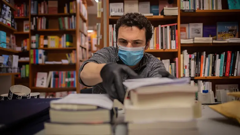 Un trabajador de la librería Laie Pau Claris librería-café ubicada en la calle catalana de Pau Claris, prepara libros y material antes de enviarlos, en una mesa del local que permanece cerrado al público por la crisis del Covid-19 pero que durante el día de hoy, sí permanece abierto para los trabajadores para prestar servicios online a los clientes que deseen obtener libros. La decisión de seguir prestando servicios online viene con motivo de la festividad tan conocida en Cataluña como el Día de Sant Jordi y la imposibilidad de poder abrir estos locales por la crisis sanitaria. En Barcelona, Cataluña, (España), a 22 de abril de 2020.

22 ABRIL 2020;CATALUNYA;CATALUÑA;BARCELONA;SANT JORDI;CORONAVIRUS;ONLINE;LIBROS;LIBRERIA

22/4/2020