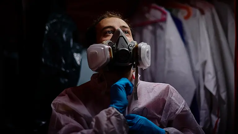 Sergio ABisambra, voluntario de SAR Navarra, se coloca un EPI para desonfectar un vehículo policial durante la crisis del coronavirus. PABLO LASAOSA