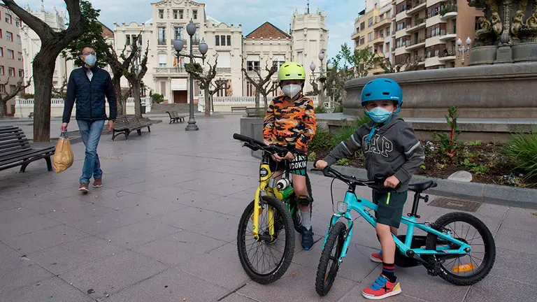 HUESCA, 26/04/2020.- Unos niños en bicicleta pasean con su padre por la calle Fatás y la plaza Navarra de Huesca, este domingo, cuando se cumplen 43 días de confinamiento, a partir del que más de seis millones de niños menores de 14 años pueden salir a la calle una hora al día, acompañados de un adulto y a un kilómetro como máximo de sus casas. EFE/ Javier Blasco
