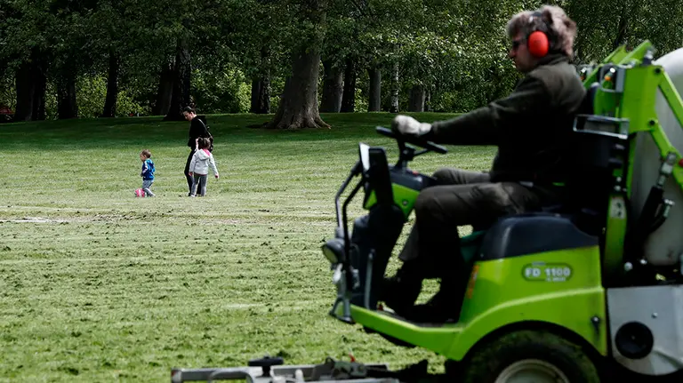 GRAFCAV5007. PAMPLONA, 29/04/2020.- Una madre pasea con sus dos hijos por el parque de la Ciudadela de Pamplona mientras un operario corta el césped, en una jornada las altas temperaturas está ya acaparando el buen tiempo que desde el sábado sera general en toda España alcanzándose temperaturas superiores a los 30 grados. Se afronta la séptima semana de confinamiento que a partir del próximo dos de mayo contara, además de los mas pequeños, con los adultos que podrán salir a pasear y también se podrá realizar actividad física individual.  EFE/ Jesús Diges
