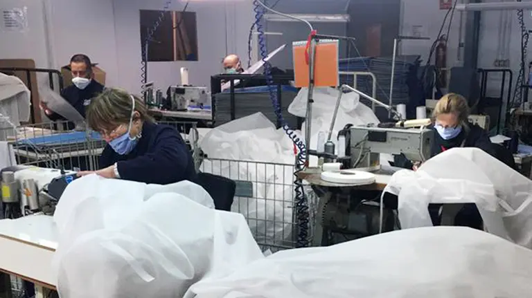 Varias personas de la asociación Animet preparando batas sanitarias. Cocemfenavarra.