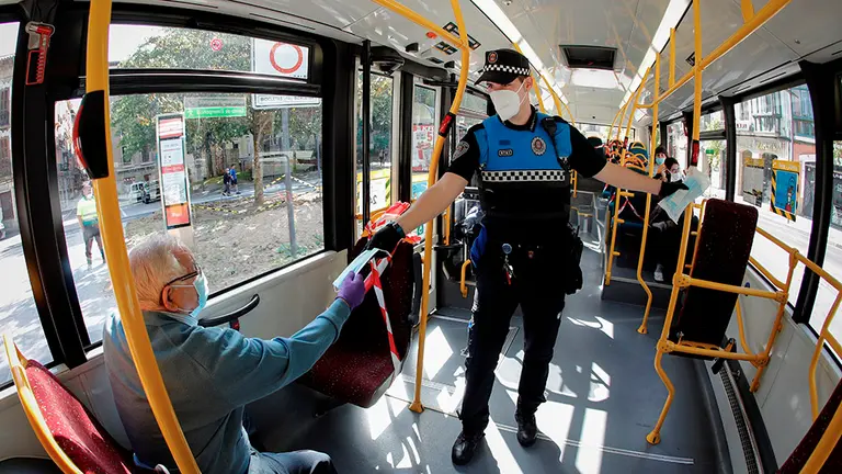 GRAFCAV5220. PAMPLONA, 04/05/2020.- Un agente de la Policía Municipal de Pamplona reparte mascarillas este lunes entre los usuarios de un autobús urbano de la capital navarra en una jornada en la que ha comenzado a primera hora de la mañana el reparto de las 84.000 mascarillas enviadas a Navarra por el Gobierno central para distribuirlas entre los usuarios del transporte público. El reparto coincide con el inicio de la Fase 0 de la desescalada, en la que es obligatorio el uso de mascarilla que cubran nariz y boca en todos los servicios de transporte público y colectivo, tanto terrestre (autobús, taxi, VTC y ferrocarril) como aéreo y marítimo. EFE/ Villar López
