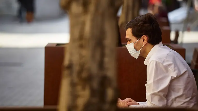 Un hombre con mascarilla descansa sentado en un banco durante el segundo día de la fase 0 de la desescalada en la que se permite la apertura con limitaciones de algunos establecimientos, en Pamplona/Navarra (España) a 5 de mayo de 2020. Europa Press.