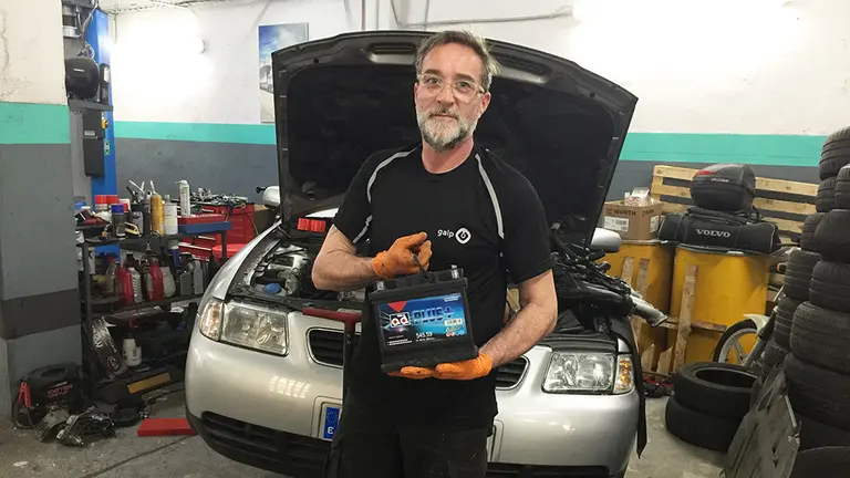 Ángel Soria sostiene una batería en su taller de reparación de vehículos Hulacar en Pamplona. Navarra.com