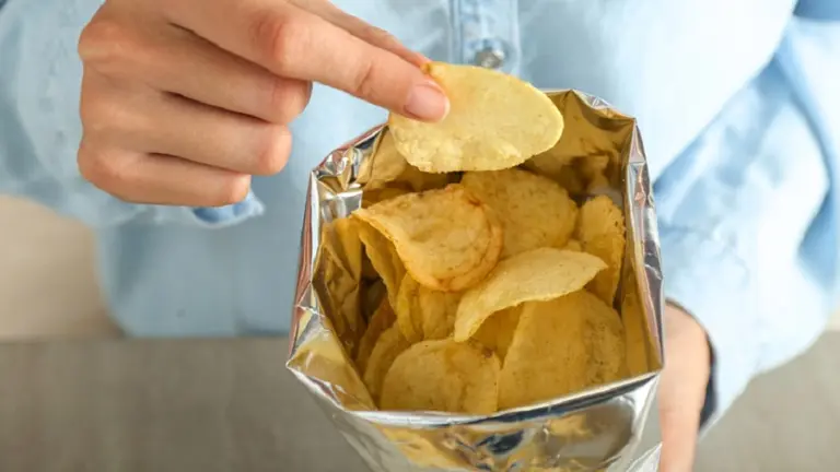 Una mujer come patatas fritas de una bolsa. ARCHIVO