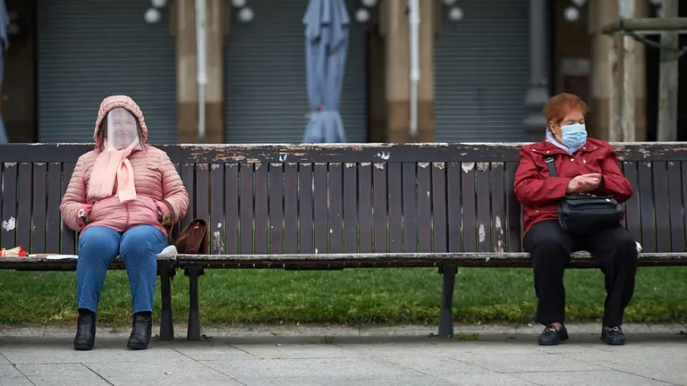 Dos señoras con mascarila y pantalla protectora descansan en la Plaza del Castillo durante la crisis del coronavirus en Pamplona. Miguel Osés