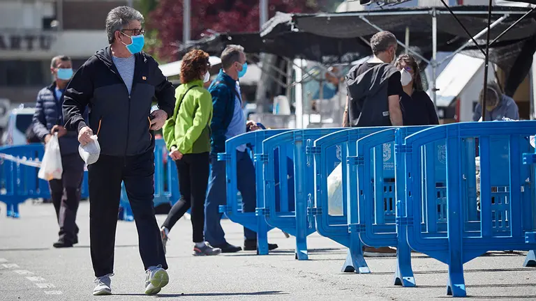 Varias personas aguardan en cola para poder entrar en el mercadillo de Pamplona el primer dia de retorno de apertura, donde Policia Municipal, SAR Navarra y Proteccion civil se han encargado de controlar el aforo, repartir mscarillas y ayudar a los dueños de los puestos a prepararse contra el covid19. En Pamplona, Navarra, España, a 17 de mayo de 2020. Europa Press.