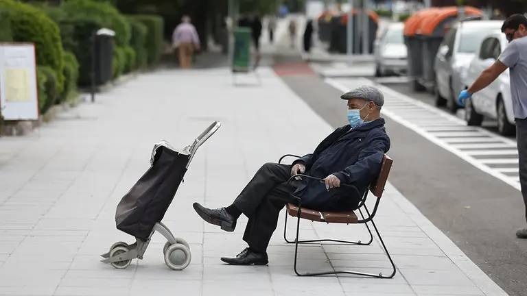 Un hombre de edad avanzada espera en un banco protegido con mascarilla y con un carro de la compra durante su franja horaria permitida en la desescalada por la crisis del Covid-19 donde aquellos mayores de 70 años pueden salir a la vía pública de 10.00 a 12.00 horas y de 19.00 a 20.00 horas. En Madrid, (España), a 7 de mayo de 2020.

07 MAYO 2020;ANCIANOS;PERSONAS DEPENDIENTES;COVID19;CORONAVIRUS;DESESCALADA;DISCAPACIDAD

7/5/2020