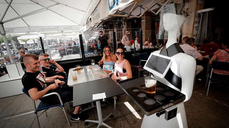 El robot Alexia sirve una consumición a unos clientes en el Bar Baviera de Pamplona. EFE/Villar Lopez.