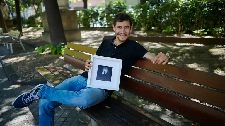 El fotógrafo pamplonés, Pablo Lasaosa, posa con su cuadro de San Fermín. MIGUEL OSÉS