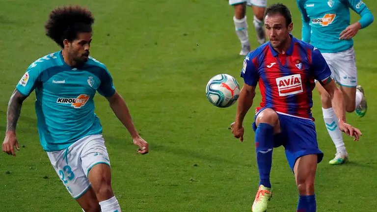 El defensa del Osasuna Aridane Hernández (i) presiona al delantero del Eibar Kike García durante el partido de la jornada 33 de LaLiga Santander de fútbol que han disputado este jueves en el estadio de Ipurua de Eibar. EFE/Javier Etxezarreta.