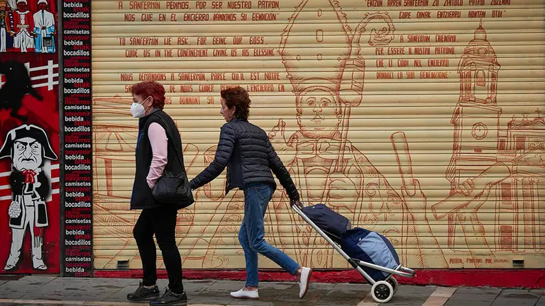 Dos personas caminan por el casco antiguo desierto a primera hora de la mañana, cuando, de celebrarse, hubieran tenido lugar los encierros de los Sanfermines, en Pamplona, Navarra (España), a 5 de julio de 2020. Pamplona afronta este lunes con medidas para intentar evitar que se produzcan aglomeraciones en la ciudad en el día en el que deberían comenzar los Sanfermines de 2020, que, sin embargo, han sido suspendidos por la pandemia de Covid-19.

06 JULIO 2020;SANFERMINES;FIESTA;TRADICIÓN;TOROS;CANCELACIÓN;COVID-19;CORONAVIRUS

6/7/2020