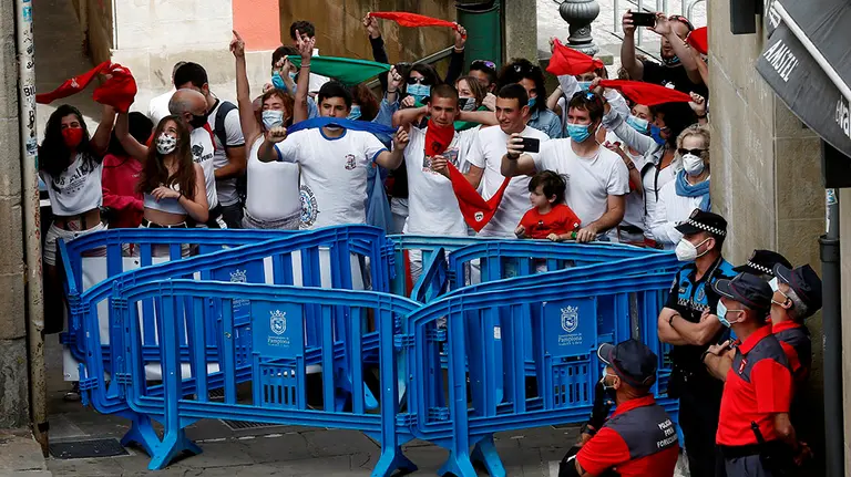 GRAFCAV7001. PAMPLONA, 06/07/2020.-  Efectivos de la Policía Foral vigilan los accesos este lunes a la Plaza del Ayuntamiento de Pamplona donde a las doce del mediodía del 6 de julio, el momento más esperado por los pamploneses, debían dar inicio los Sanfermines de 2020. El momento esperado en la plaza Consistorial por un número controlado de personas, debido a la limitación de aforo establecida con motivo de la COVID-19, ha sido seguido con aplausos y gritos, unas muestras de alegría y tristeza, a la vez, que se han sucedido en diferentes puntos de la ciudad, donde numerosos pamploneses han quedado como es habitual en estas fechas para almorzar. EFE/ Jesús Diges
