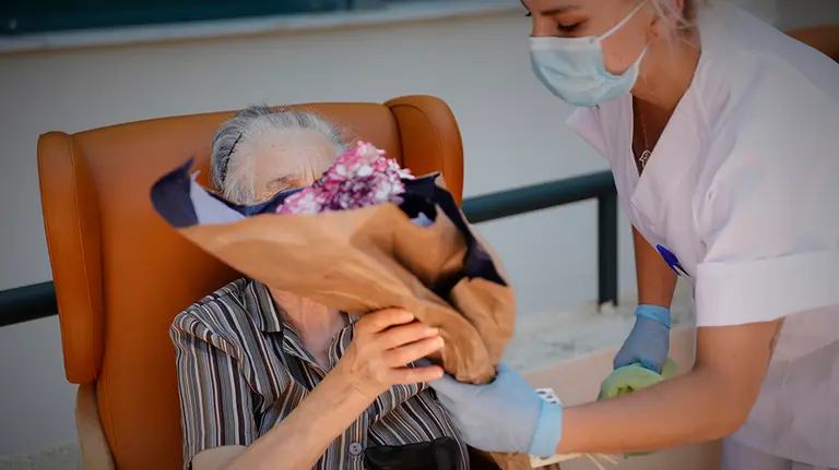 Una residente de la Residencia de Mayores Pablo Neruda (C/ Santa Clara, 1, Ciempozuelos, Madrid) recibe un ramo de flores durante el "Día de los Mayores", una celebración convocada por la Asociación de Víctimas del COVID-19. En Ciempozuelos, Madrid (España) a 28 de junio de 2020. Durante este día se reparten regalos benéficos en las residencias en lotes de productos, y se dedica una adaptación musical de la canción “Contigo aprendí…” realizada por las periodistas y cantantes Candela Palazón y Celia Blanco.

28 JUNIO 2020 MAYORES;ANCIANOS;CORONAVIRUS;MASCARILLAS

28/6/2020