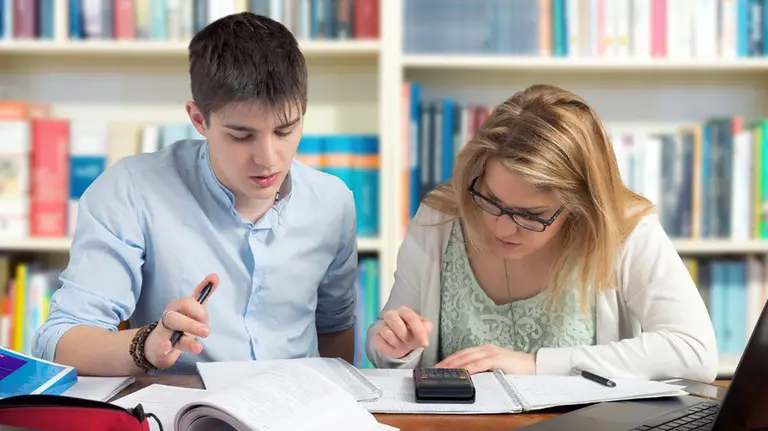 Dos jóvenes estudian en una biblioteca. ARCHIVO
