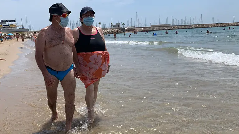 Dos personas caminan por la orilla de mar en una playa portando sus mascarillas durante el verano de la crisis del coronavirus. NAVARRACOM