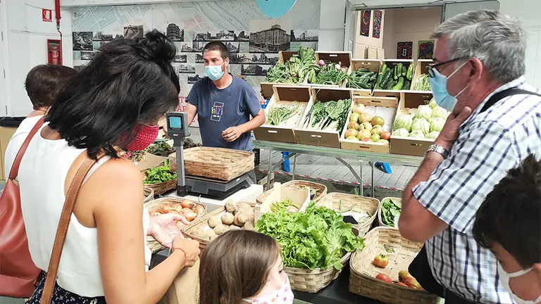 Varias personas comprando en un puesto de verdura del quinto EKOmercado de Pamplona