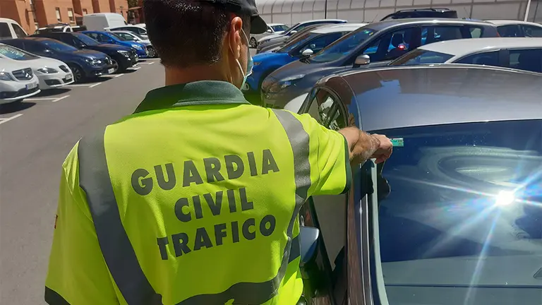 Un agente de la Guardia Civil señala la pegatina ITV de un vehículo. GUARDIA CIVIL