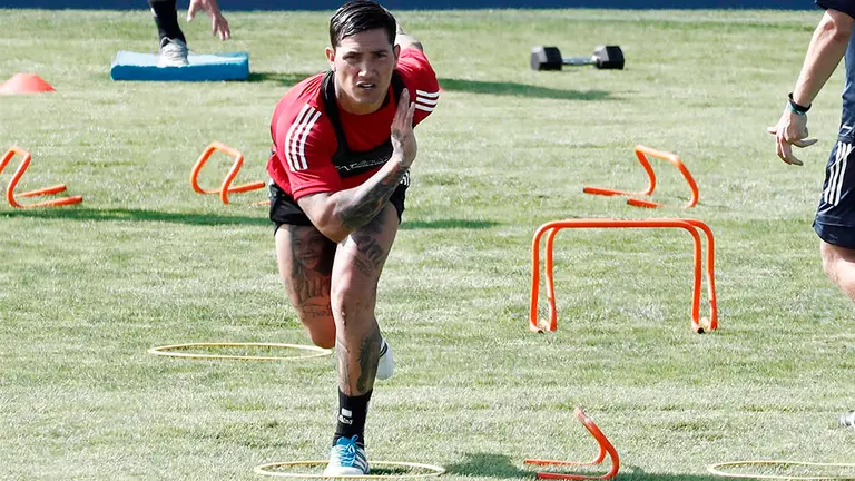 GRAFCAV8004. PAMPLONA, 13/08/2020.- El delantero argentino de Osasuna Luiz Ezequiel "Chimy" Ávila, junto a uno de los preparadores del equipo rojillo, realiza varios ejercicios en el césped de las instalaciones de Tajonar donde, de forma escalonada y por grupos, han comenzado los jugadores el primer entrenamiento de la pretemporada.  EFE/ Jesús Diges
