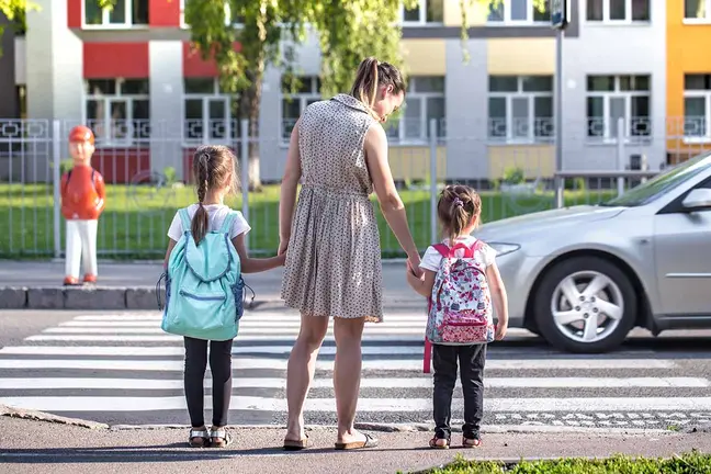 Back to school education concept with girl kids, elementary students, carrying backpacks going to class on school first day holding hand in hand together walking up building stair happily