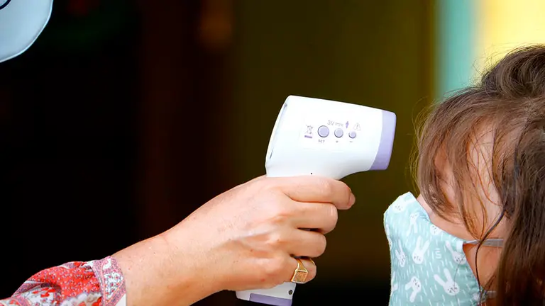 Una profesora toma la temperatura a una niña antes de entrar al colegio. EFE/ Salas